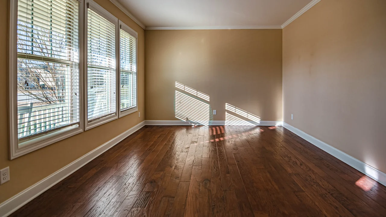 An empty room in Anthem with new dark hardwood flooring laid straight to the walls